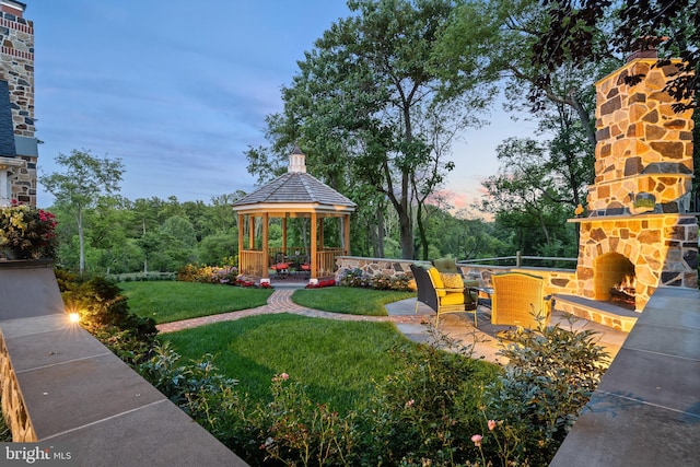 view of yard with an outdoor stone fireplace, a gazebo, and a patio area