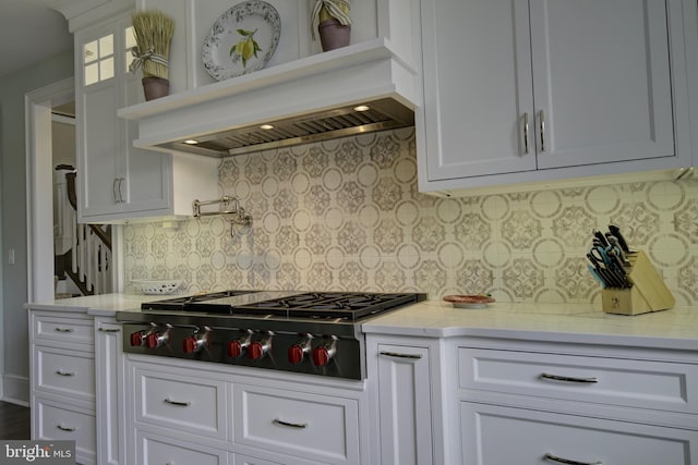 kitchen with stainless steel gas cooktop, white cabinetry, premium range hood, and tasteful backsplash