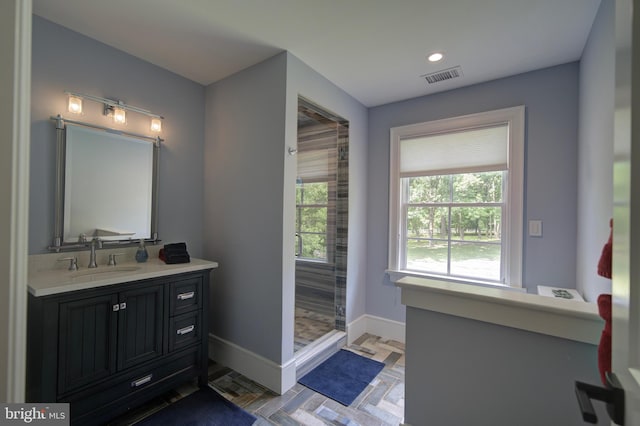 full bath with a healthy amount of sunlight, baseboards, vanity, and visible vents