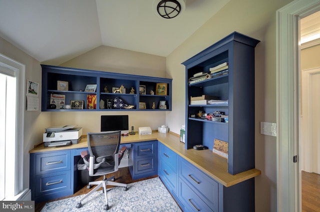 office space with built in study area, lofted ceiling, and wood finished floors