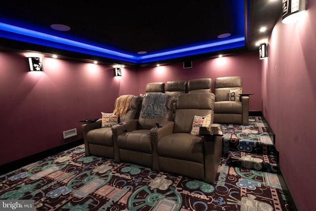 carpeted cinema room featuring a tray ceiling and visible vents