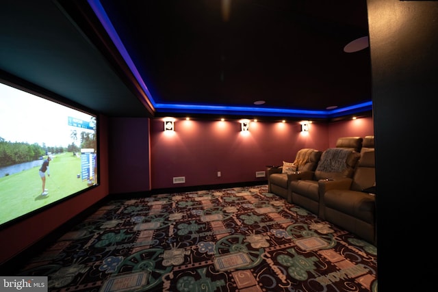 home theater with baseboards, a tray ceiling, and visible vents