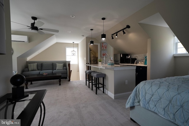 bedroom with light colored carpet, an AC wall unit, rail lighting, freestanding refrigerator, and vaulted ceiling