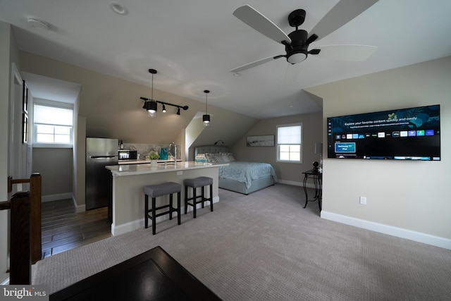 bedroom featuring a sink, baseboards, freestanding refrigerator, and vaulted ceiling