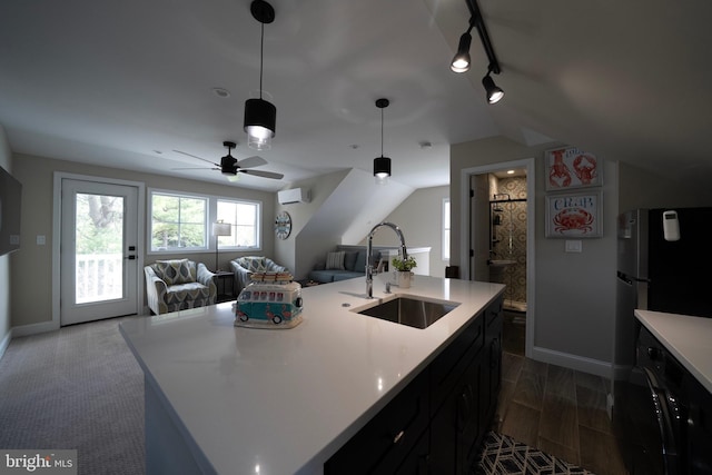 kitchen featuring a sink, an AC wall unit, rail lighting, baseboards, and open floor plan