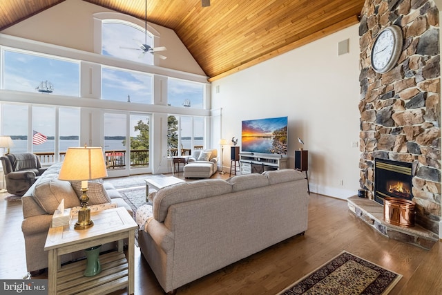 living area featuring wooden ceiling, a healthy amount of sunlight, a stone fireplace, and high vaulted ceiling