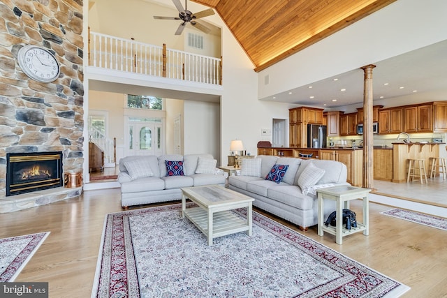 living room featuring wood ceiling, light wood-type flooring, ceiling fan, visible vents, and high vaulted ceiling