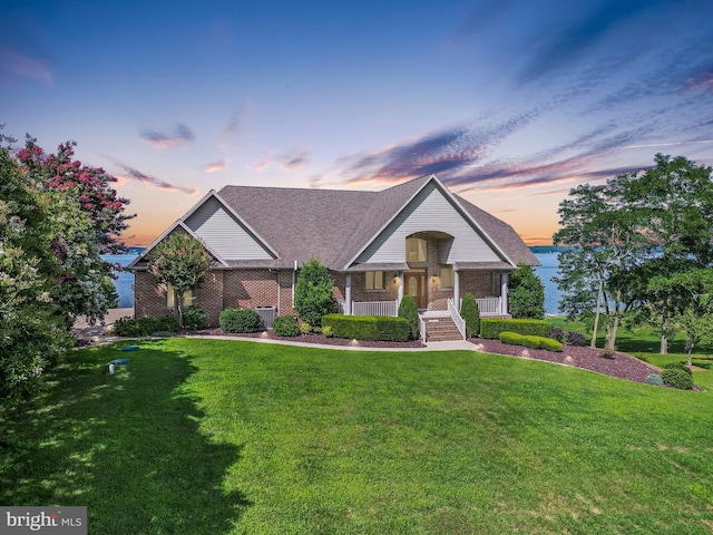 view of front of house with a porch, a front lawn, central air condition unit, and brick siding