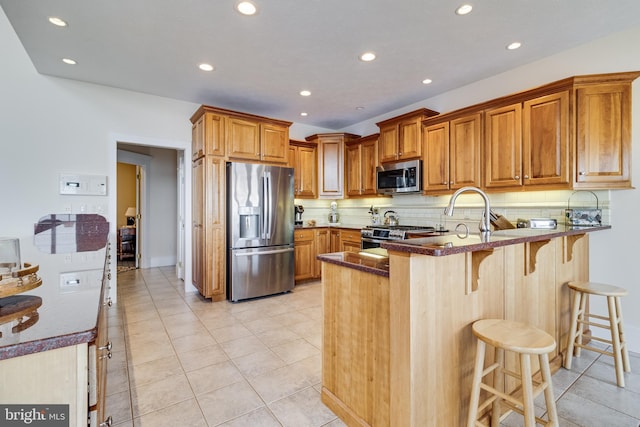 kitchen with recessed lighting, a peninsula, appliances with stainless steel finishes, and brown cabinetry