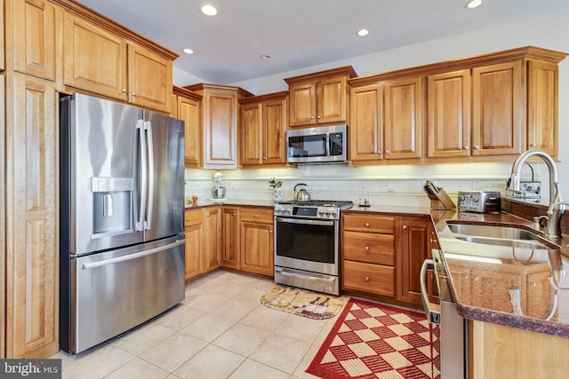 kitchen with dark stone counters, decorative backsplash, a sink, stainless steel appliances, and recessed lighting