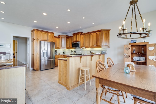 kitchen with a kitchen breakfast bar, appliances with stainless steel finishes, recessed lighting, a peninsula, and a notable chandelier
