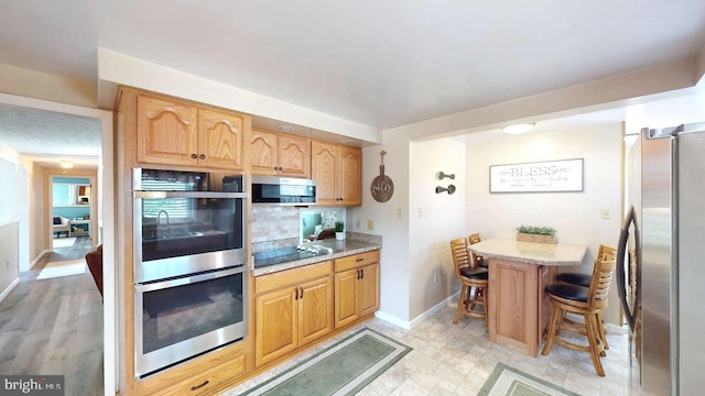 1550 Beacon St, Keyser, WV 26726 - kitchen featuring light stone countertops, appliances with stainless steel finishes, a breakfast bar area, baseboards, and tasteful backsplash
