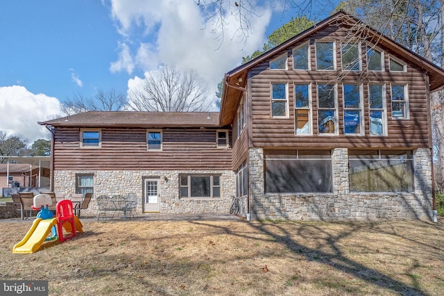 back of house with a yard, stone siding, log siding, and a shingled roof