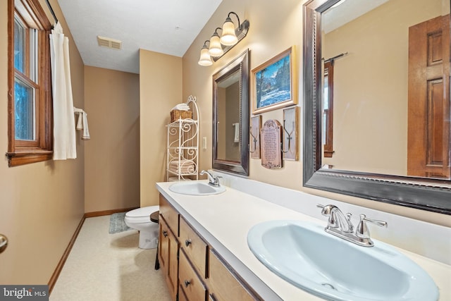 bathroom with baseboards, toilet, a sink, and visible vents