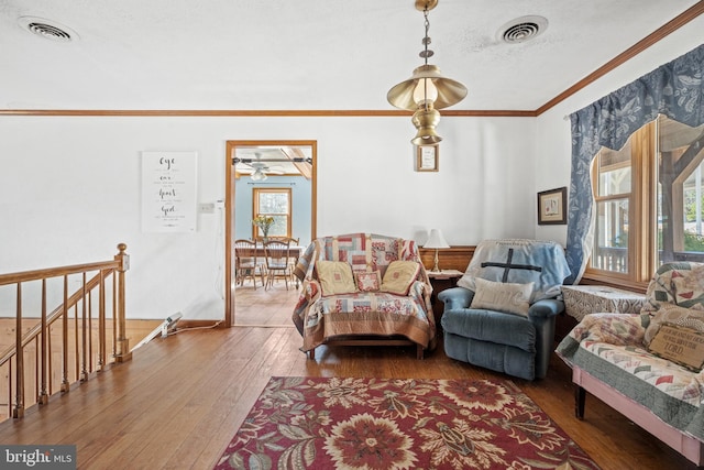 living room with ceiling fan, crown molding, hardwood / wood-style floors, and visible vents
