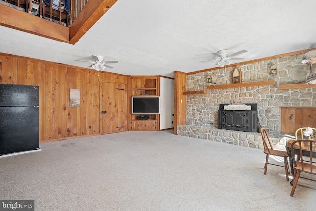 carpeted living area with a fireplace, wooden walls, ornamental molding, and ceiling fan
