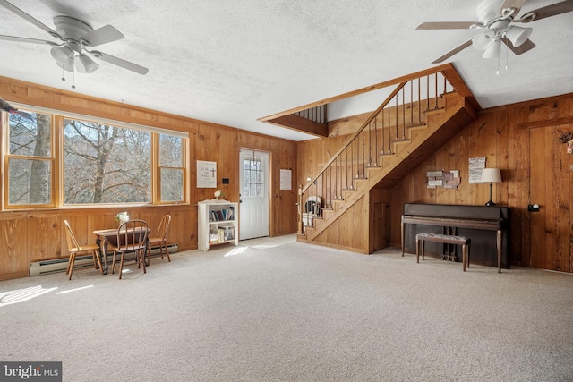living area with wooden walls, a ceiling fan, and baseboard heating