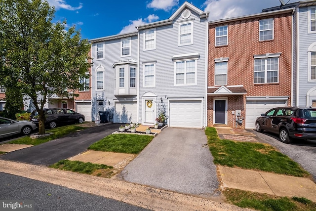 townhome / multi-family property with a garage, driveway, and brick siding