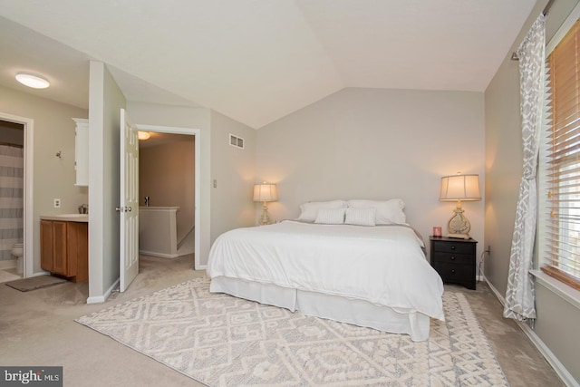 bedroom with light carpet, vaulted ceiling, visible vents, ensuite bathroom, and baseboards