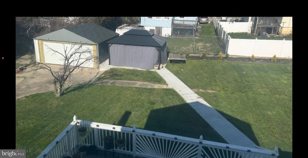 view of yard featuring a garage, an outdoor structure, fence private yard, and driveway