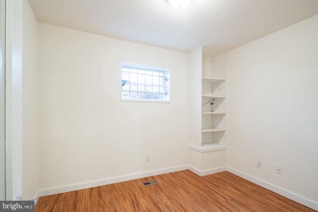 unfurnished room with baseboards, wood finished floors, and visible vents