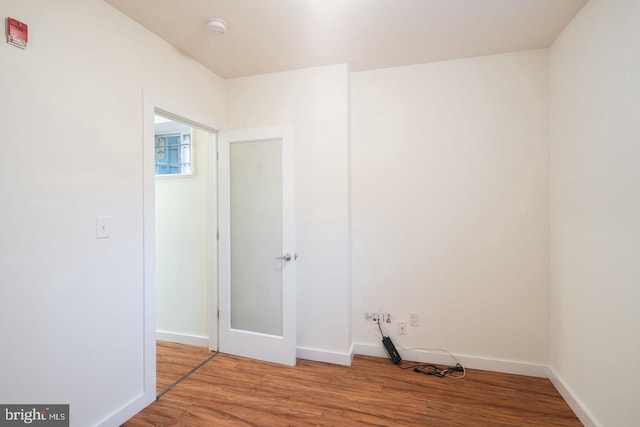 spare room with baseboards and wood finished floors
