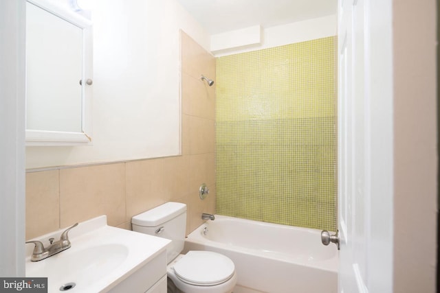 full bath with tile walls, toilet, vanity, and shower / tub combination