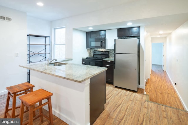 kitchen featuring a sink, black appliances, light wood-type flooring, baseboards, and visible vents