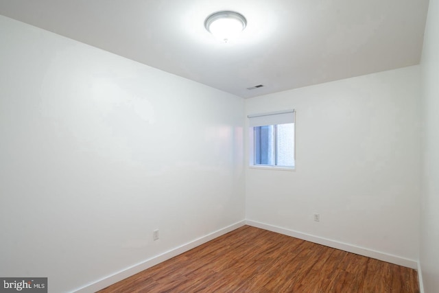 spare room featuring baseboards, wood finished floors, and visible vents
