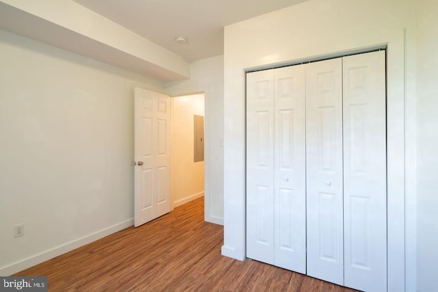 unfurnished bedroom featuring baseboards, wood finished floors, and a closet