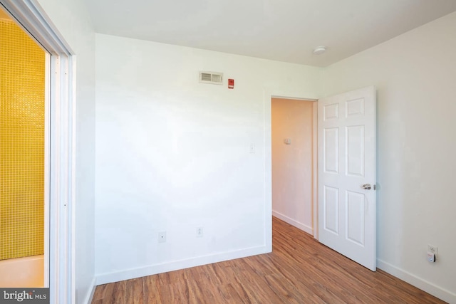 spare room featuring baseboards, wood finished floors, and visible vents