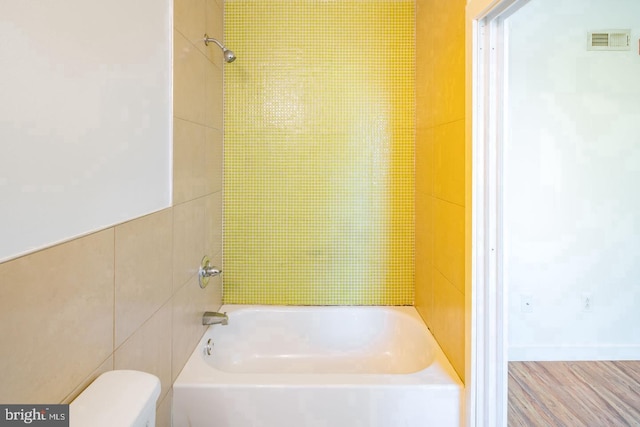 bathroom featuring toilet, wood finished floors, shower / tub combination, and visible vents