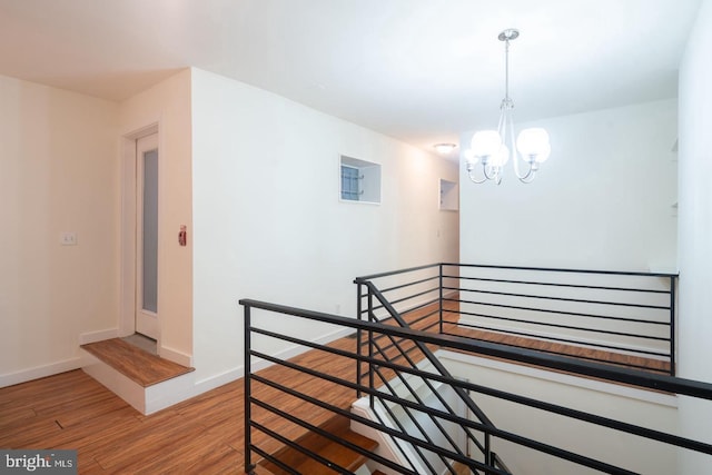 interior space with baseboards, a notable chandelier, and wood finished floors
