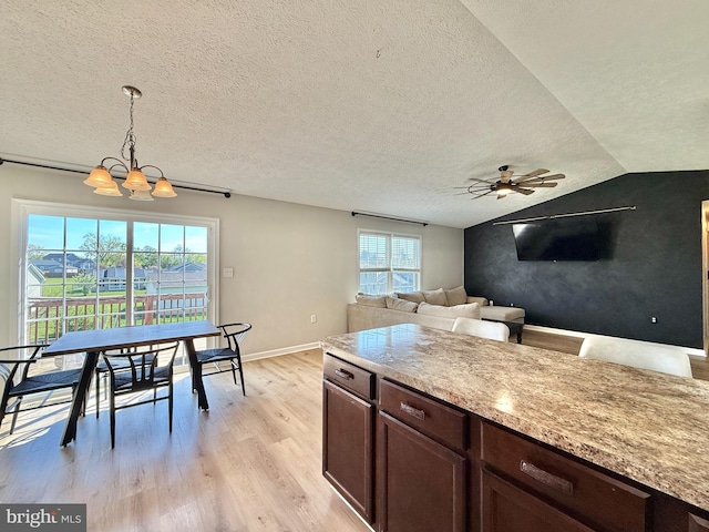 kitchen with light wood-style flooring, decorative light fixtures, dark brown cabinets, ceiling fan with notable chandelier, and a textured ceiling