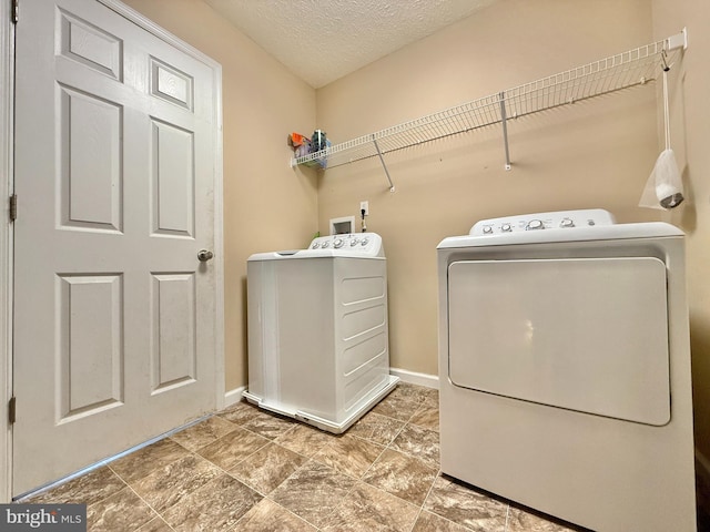 laundry room featuring baseboards, a textured ceiling, laundry area, and washing machine and dryer