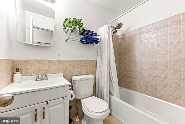 bathroom featuring vanity, shower / bath combo with shower curtain, toilet, tile walls, and a wainscoted wall