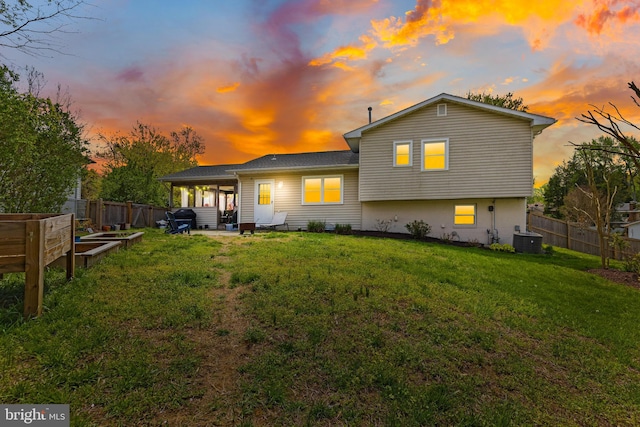 back of property with a fenced backyard, central air condition unit, a yard, and a vegetable garden