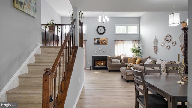 46932 Trumpet Cir, Sterling, VA 20164 - living room with stairs, a lit fireplace, a chandelier, light wood-style flooring, and a towering ceiling