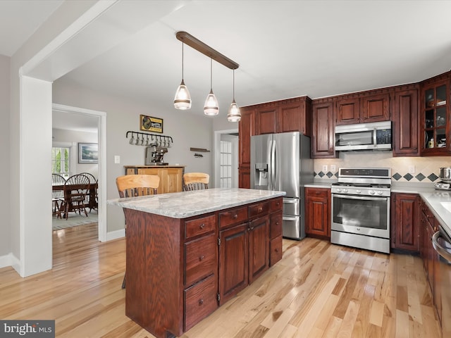 12943 Harford Rd, Hydes, MD 21082 - kitchen featuring appliances with stainless steel finishes, light wood-style flooring, hanging light fixtures, backsplash, and glass insert cabinets