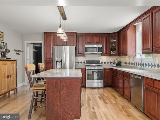 12943 Harford Rd, Hydes, MD 21082 - kitchen featuring appliances with stainless steel finishes, a sink, decorative backsplash, light wood-style flooring, and a center island