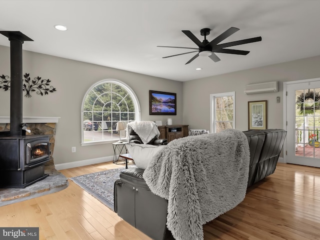 12943 Harford Rd, Hydes, MD 21082 - living area featuring a wall mounted AC, wood finished floors, ceiling fan, a wood stove, and baseboards
