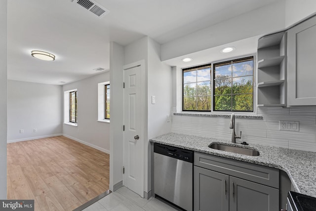 kitchen featuring light stone counters, a sink, gray cabinets, stainless steel dishwasher, and visible vents