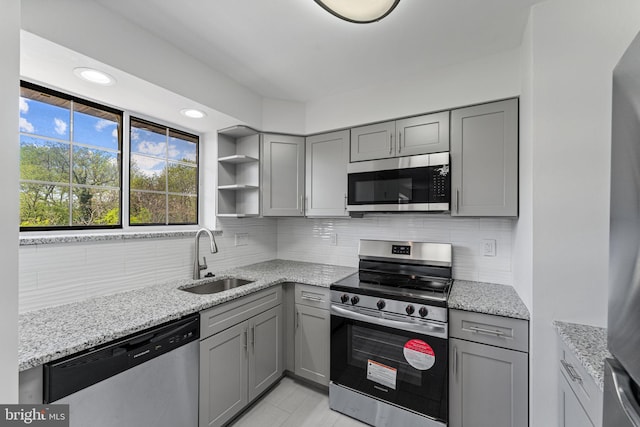 kitchen featuring stainless steel appliances, a sink, and gray cabinets