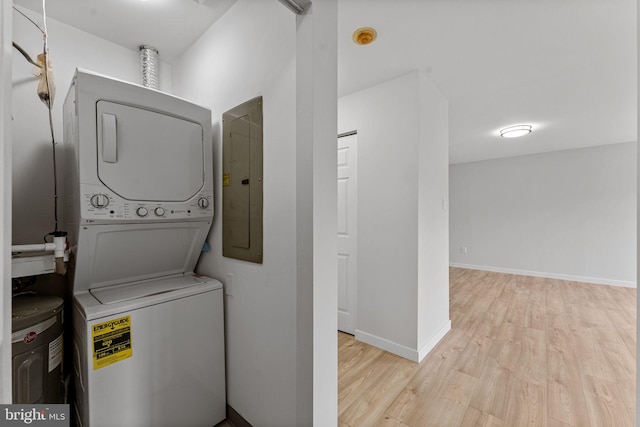 washroom with laundry area, baseboards, wood finished floors, stacked washer and clothes dryer, and electric panel