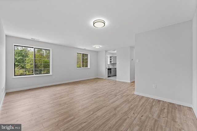 unfurnished living room with baseboards, visible vents, and light wood-type flooring