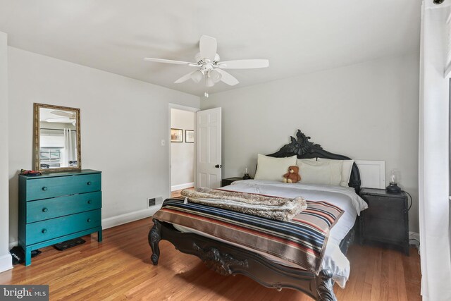 bedroom featuring baseboards, a ceiling fan, wood finished floors, and visible vents