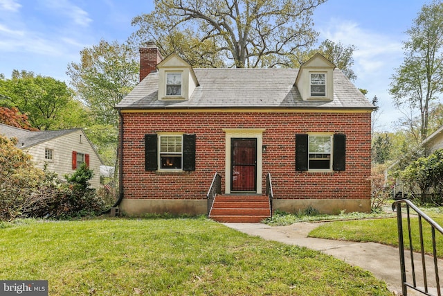 new england style home with a chimney, a front lawn, and brick siding