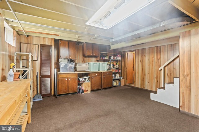 kitchen featuring wooden walls, brown cabinets, dark carpet, and light countertops