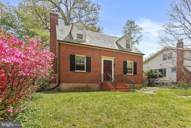 cape cod home with a chimney, a front lawn, and brick siding