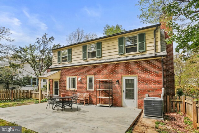 back of property with brick siding, fence, central AC unit, and a chimney
